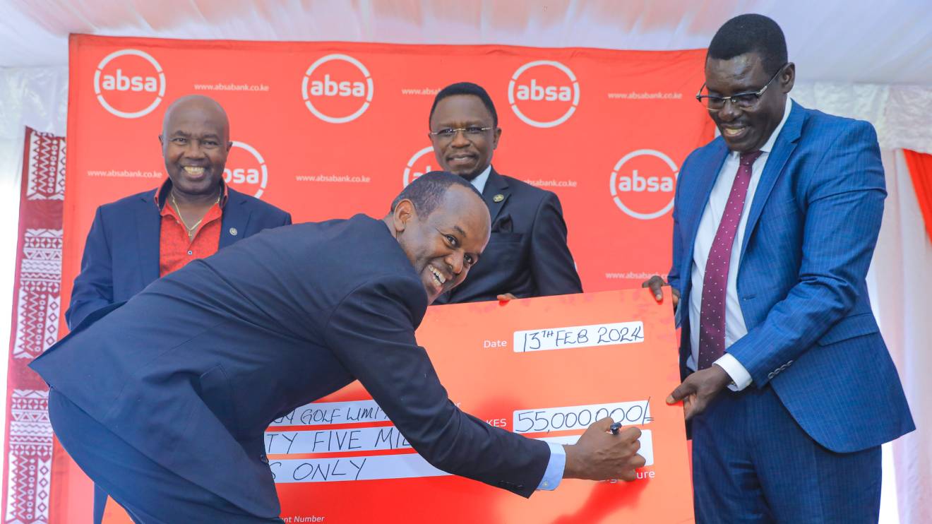 Absa Bank MD Abdi Mohamed appends his signature on the dummy cheque as KOGL's Patrick Obath, CS Ababu Namwamba and PS Peter Tum watch on. PHOTO/COURTESY